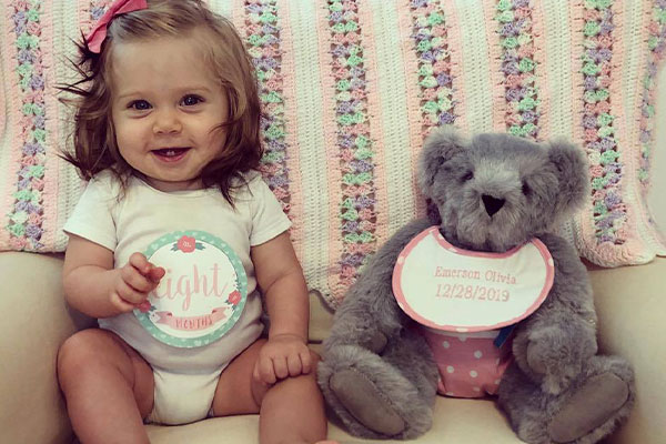 An image of a baby playing with a 15-inch Baby Girl Bear