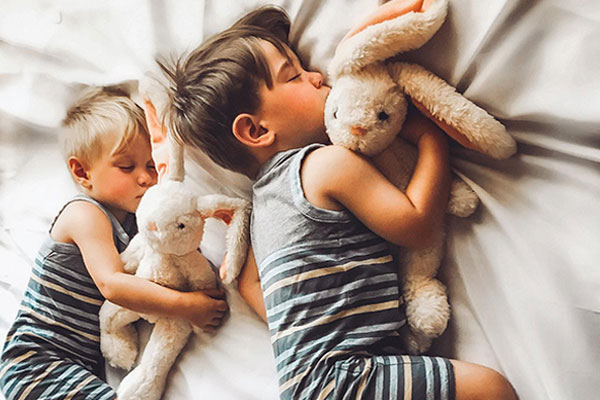 An image of 2 sleeping children cuddling with The World's Softest Bunny bears