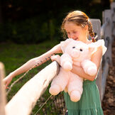 18" Oh So Soft Pig - Full length view of soft plush pink pig with model in outdoor setting image number 7