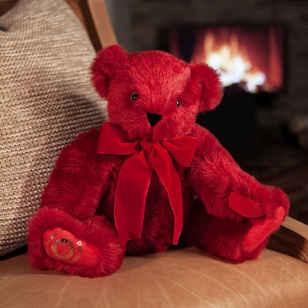 20" Special Edition 40th Anniversary Bear - Seated jointed ruby red bear with red pads and gold Vermont Teddy Bear logo on right foot with red bow in a living room setting