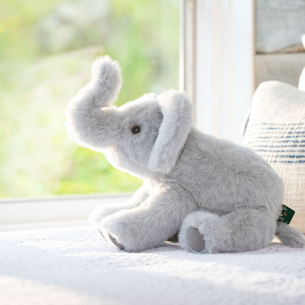 15" Classic Elephant - Seated side view of gray plush elephant with upturned trunk and pink mouth looking out a window image number 5