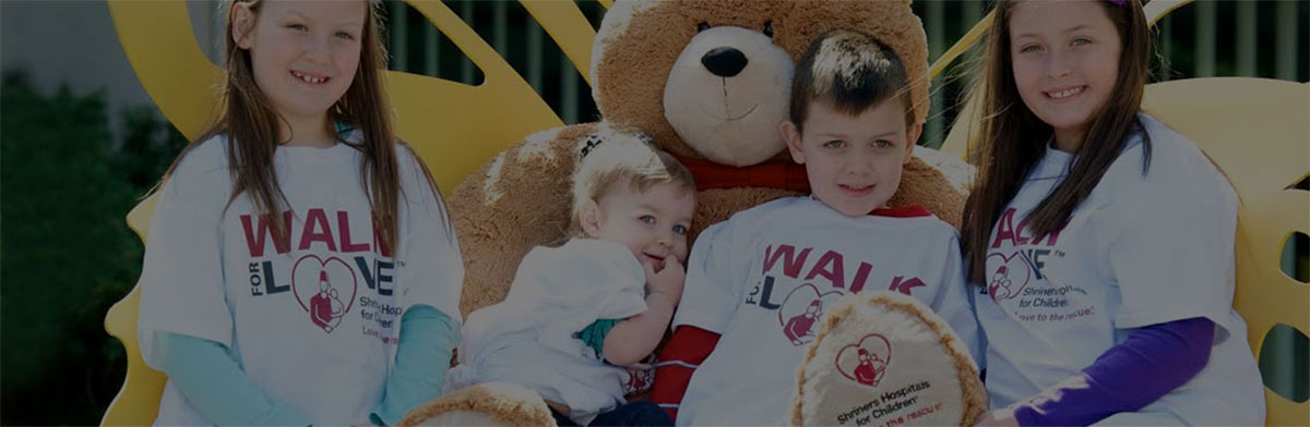 An image of children sitting with the 4-foot Love to the Rescue Bear