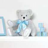 15" Premium Baby Boy Bear - Front view of seated jointed gray bear with white paw pads and chose of eye color wearing a blue satin bow in a bedroom scene.  image number 1