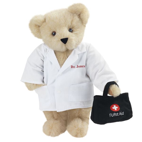 15" Doctor Bear - Front view of standing jointed bear dressed in white labcoat holding a doctor bag that is embroidered wth "FURst Aid" and a medical cross in red and white personalized with "Dr. Jones" on left chest in red - Buttercream brown fur image number 1