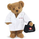 15" Doctor Bear - Front view of standing jointed bear dressed in white labcoat holding a doctor bag that is embroidered wth "FURst Aid" and a medical cross in red and white personalized with "Dr. Jones" on left chest in red - Honey brown fur image number 0