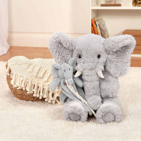 18" Oh So Soft Elephant with Elephant Lovey Security Blanket - Front view of seated soft gray elephant holding a gray baby elephant blanket with wrist strap in living room setting image number 1